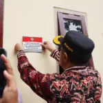 Bupati Banyumas Sadewo Tri Lastiono menempelkan stiker di tembok rumah warga yang menerima bantuan renovasi RTLH, sebagai simbolis penyerahan rumah yang telah di renovasi, Rabu (12/11/2025).
