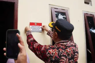 Bupati Banyumas Sadewo Tri Lastiono menempelkan stiker di tembok rumah warga yang menerima bantuan renovasi RTLH, sebagai simbolis penyerahan rumah yang telah di renovasi, Rabu (12/11/2025).