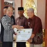 Bupati Banyumas, Sadewo Tri Lastiono, menyerahkan secara simbolis Penghargaan Optimalisasi PKB 2025 di Pendopo Si Panji, Purwokerto, Kamis (18/12/2025).