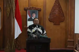 Wabup Dimas Prasetyahani menyampaikan paparan dalam High Level Meeting (HLM) Tim Pengendalian Inflasi Daerah (TPID) dan Tim Percepatan dan Perluasan Digitalisasi Daerah (TP2DD) Kabupaten Purbalingga,di Operation Room Graha Adiguna,Selasa (16/12/2025). (Foto: Budi Pekerti).
