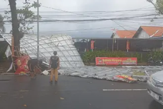 Petugas dan warga saat evakuasi atap rumah makan yang terbang ke jalan akibat hujan dan angin kencang. (BPBD Cilacap).
